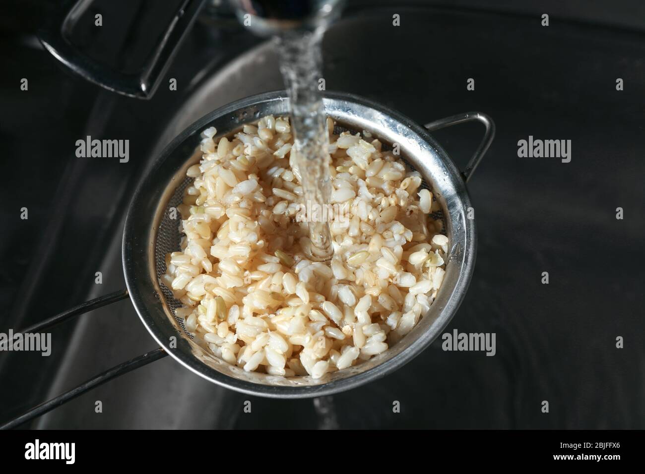 Washing brown rice with water in sieve Stock Photo Alamy