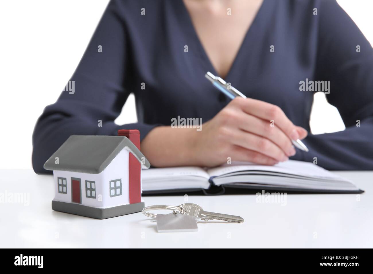 Model of house with key and woman on background Stock Photo - Alamy