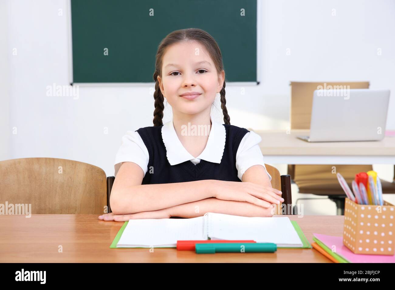 Portrait of beautiful elementary schoolgirl sitting in classroom Stock ...