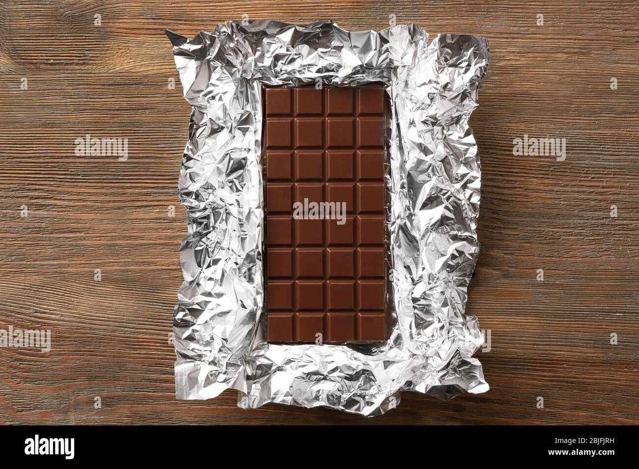 Chocolate bar in foil on wooden background Stock Photo - Alamy