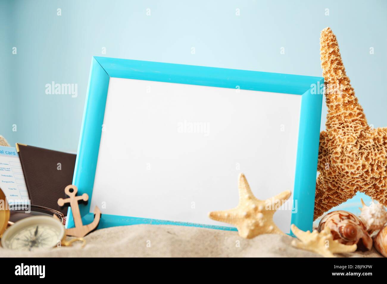 Travel concept. Composition of marine symbols and blank photo frame on sand, closeup Stock Photo