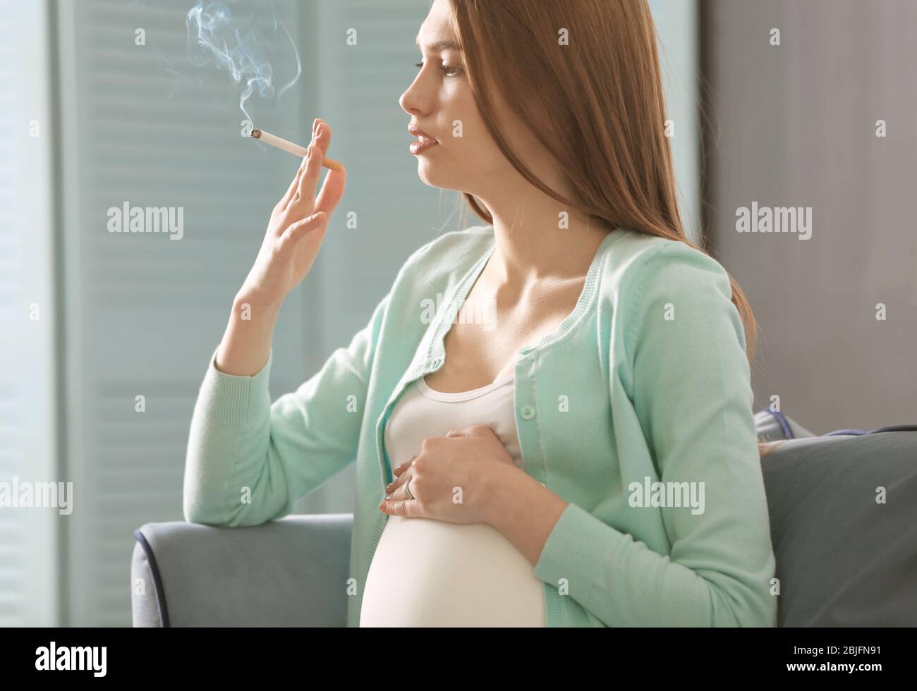 Pregnant woman smoking cigarette at home Stock Photo - Alamy