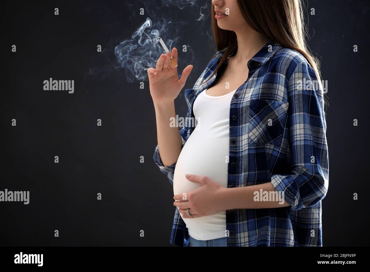Pregnant woman smoking cigarette on dark background Stock Photo Alamy