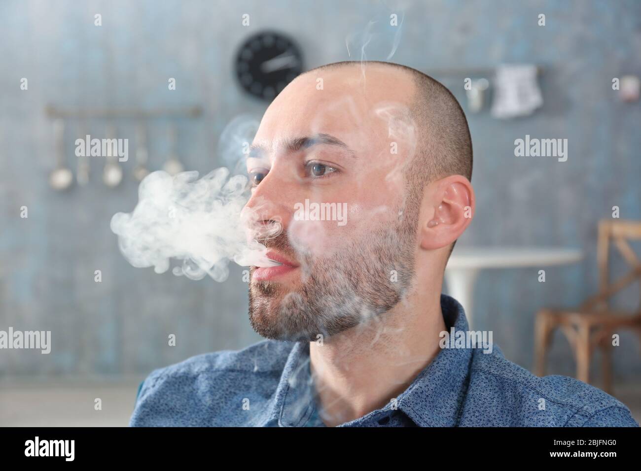 Handsome man smoking cigarette at home Stock Photo