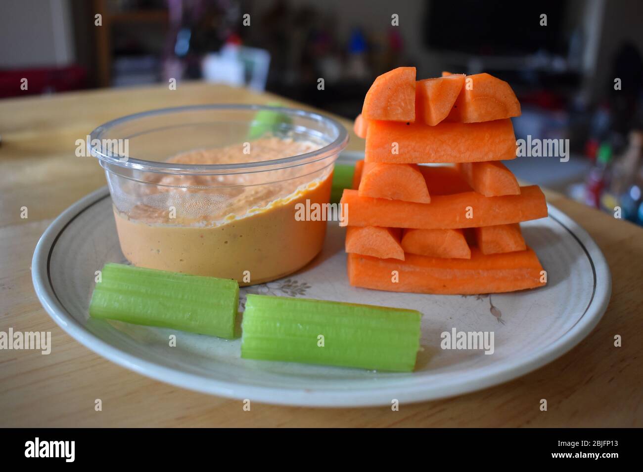 Carrots pyramid celery sticks ready to dip in hummus. Thick mixture of