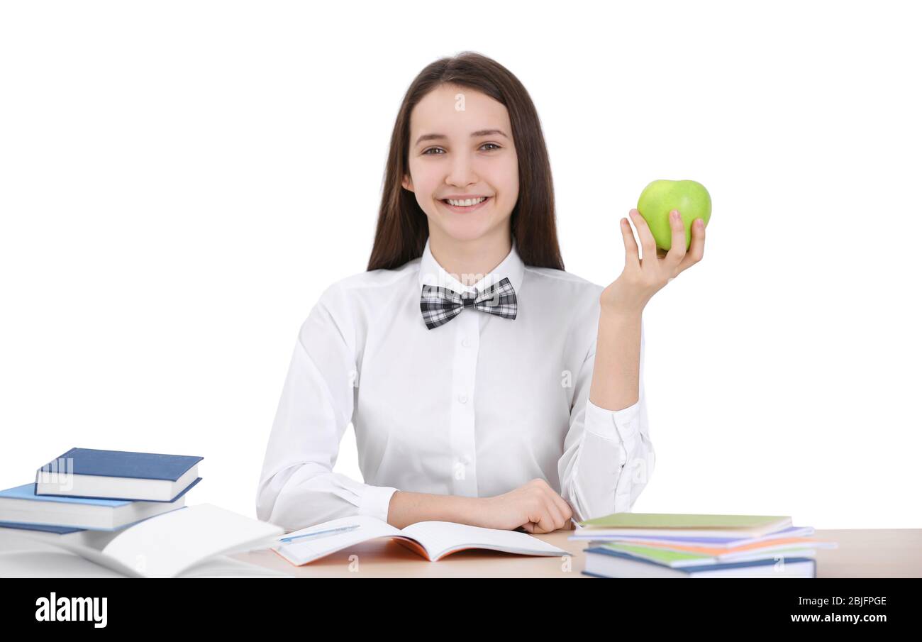 Cute schoolgirl with apple sitting at table in classroom Stock Photo ...