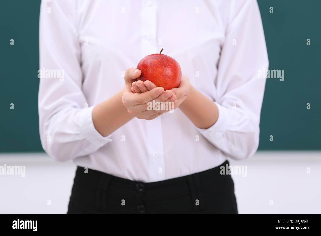 Cute schoolgirl with apple in classroom, closeup Stock Photo - Alamy