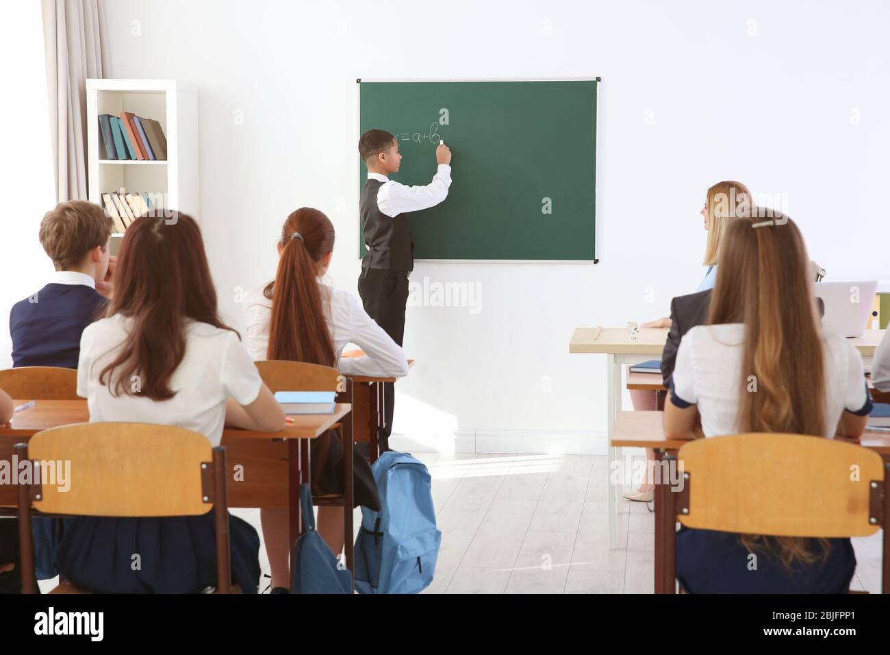 Schoolboy answering at blackboard in classroom Stock Photo Alamy