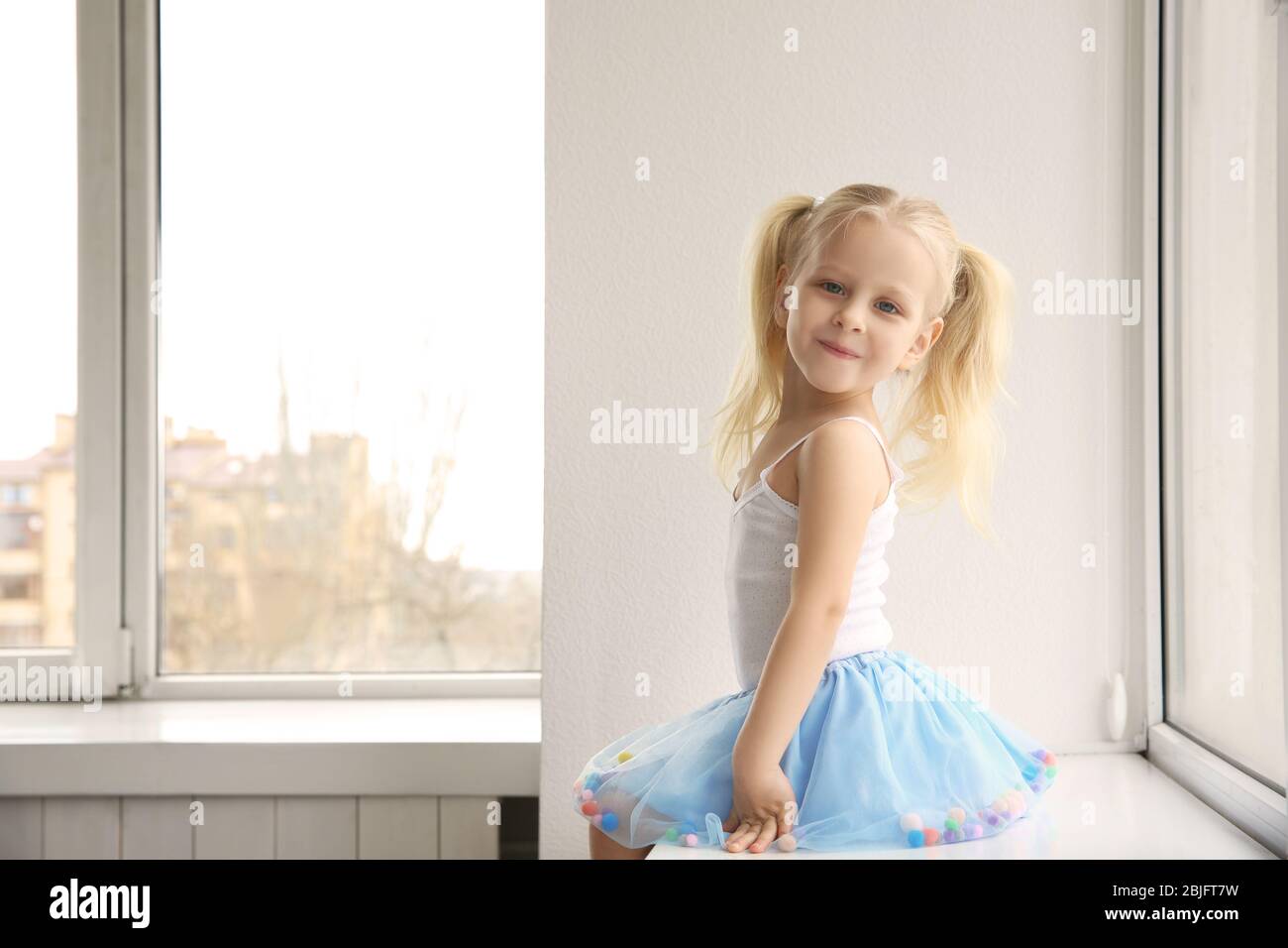 Cute little girl sitting on windowsill Stock Photo - Alamy