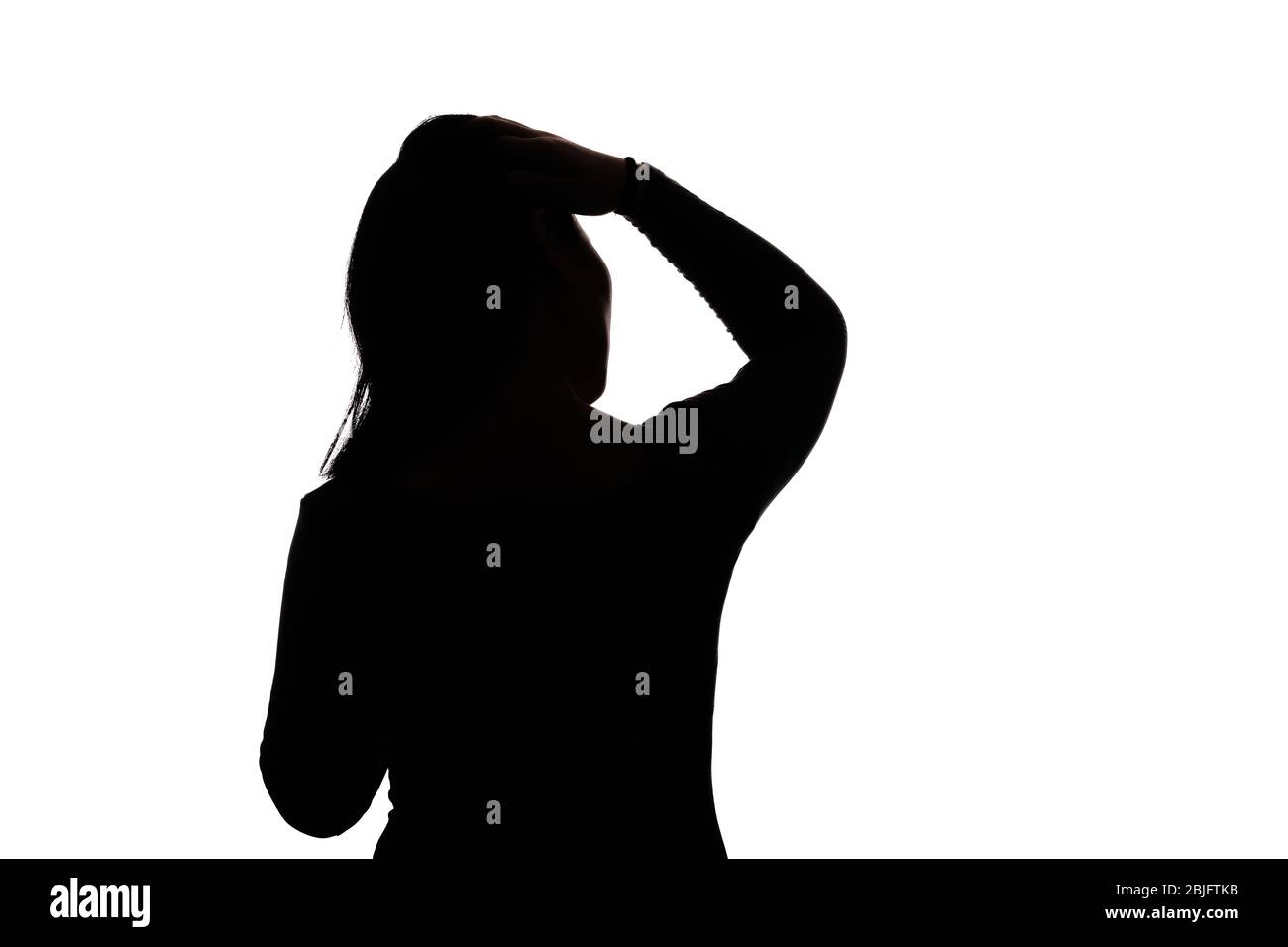 Black backlit silhouette of head and shoulders of an oriental woman from the side outlined by light Stock Photo