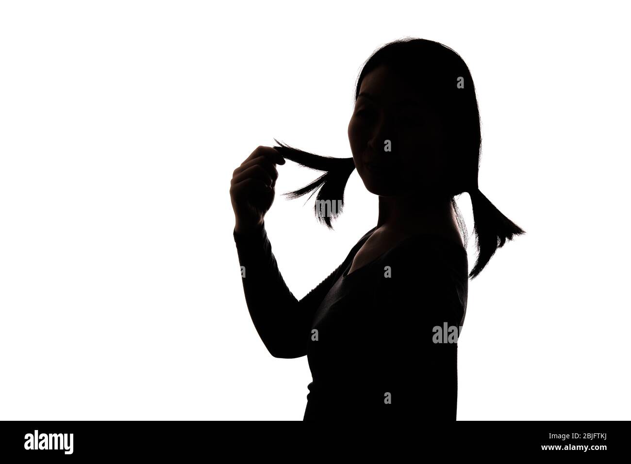 Black backlit silhouette of head and shoulders of an oriental woman from the side outlined by light Stock Photo