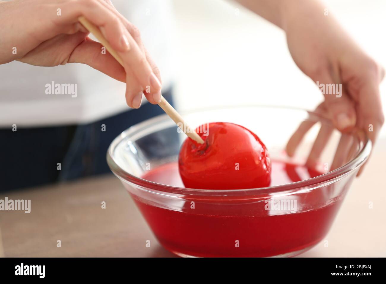 Woman dipping candy apple into glass bowl with caramel Stock Photo Alamy