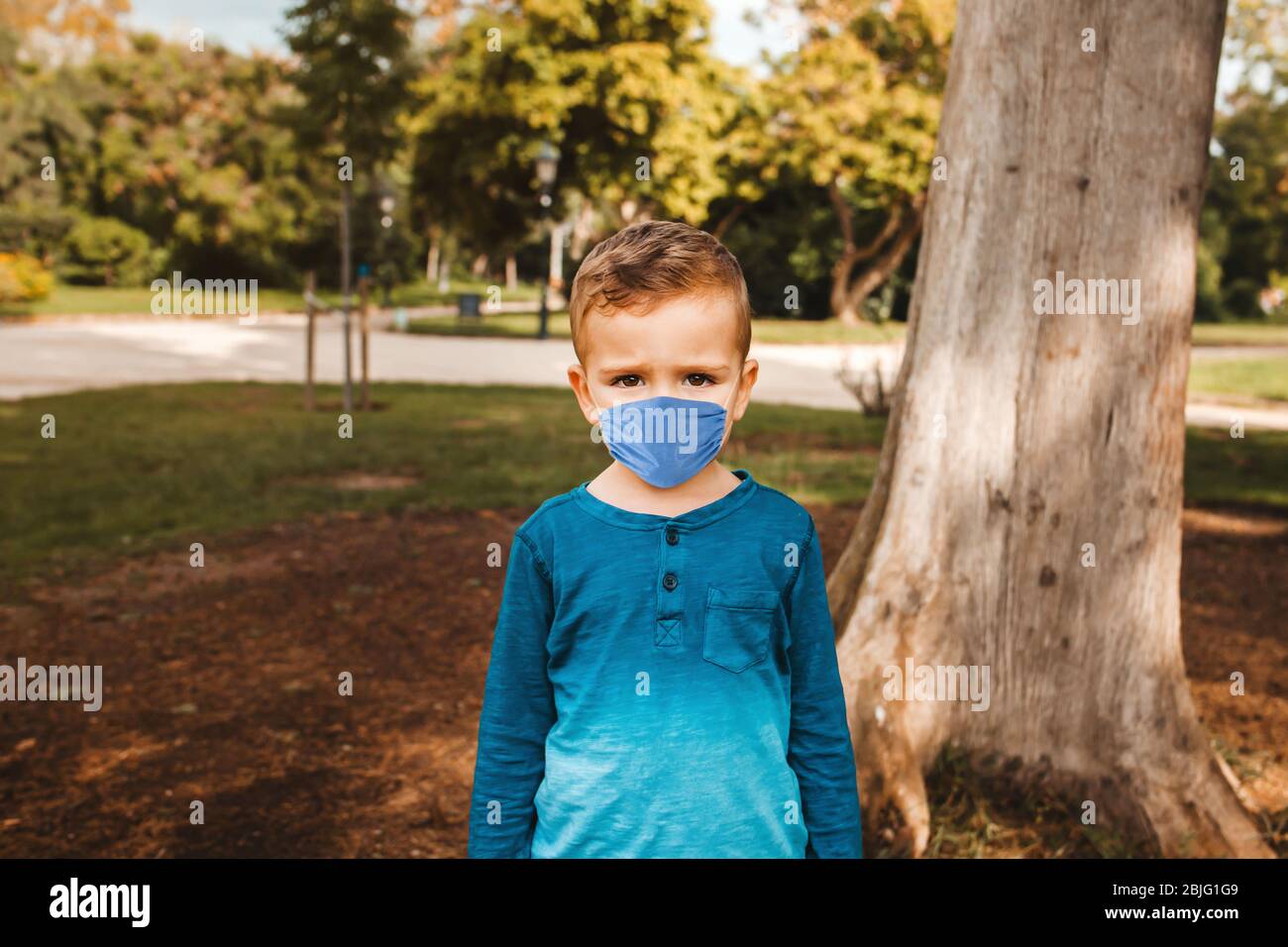 kid wearing face mask in a park against contagious coronavirus and to prevent infection or respiratory illness pandemic, social distancing Stock Photo