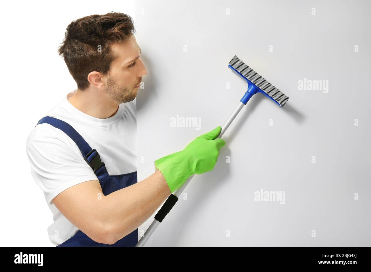 Young window cleaner with poster on white background Stock Photo