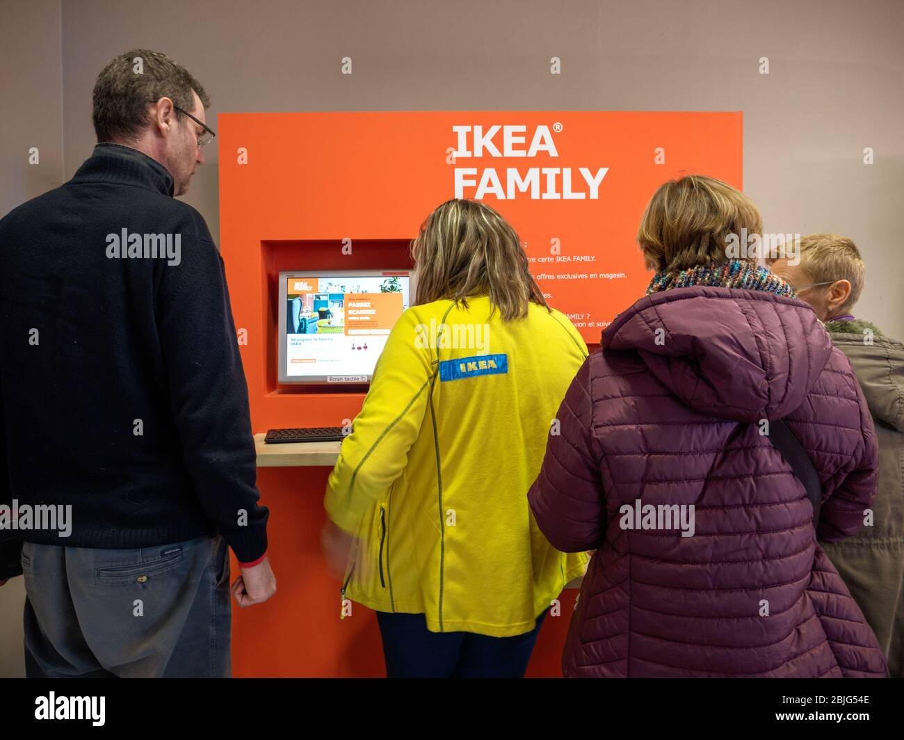 Paris, France - Dec 9, 2017: Rear view of people in front of the digital kiosk at IKEA store generating new IKEA family membership card Stock Photo