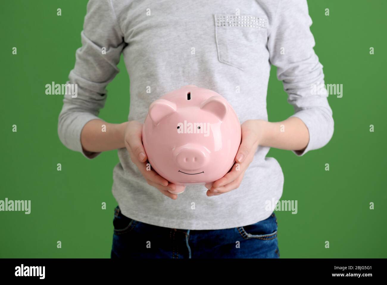 Cute girl with piggy bank on color background, closeup Stock Photo - Alamy