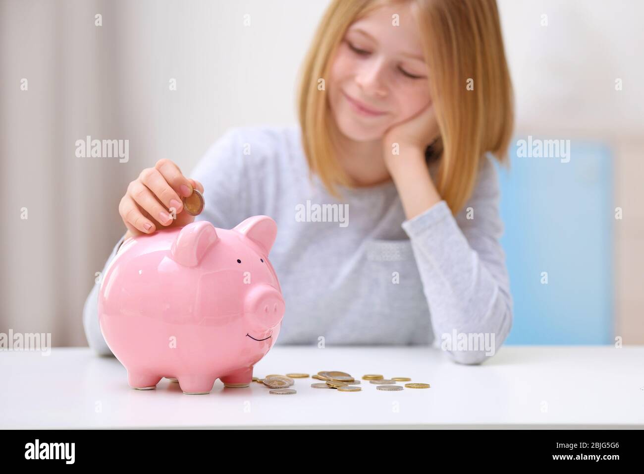 Cute girl with piggy bank and coins at home Stock Photo - Alamy
