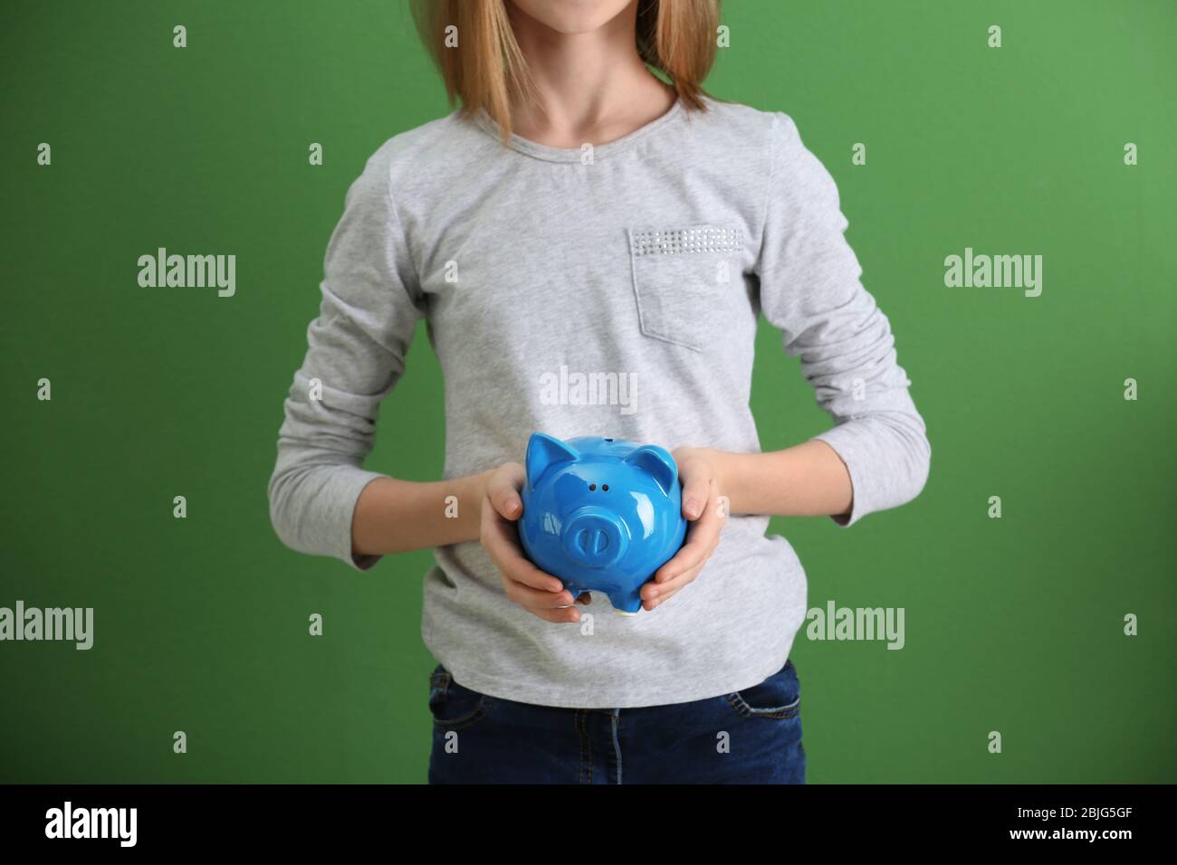 Cute girl with piggy bank on color background Stock Photo - Alamy