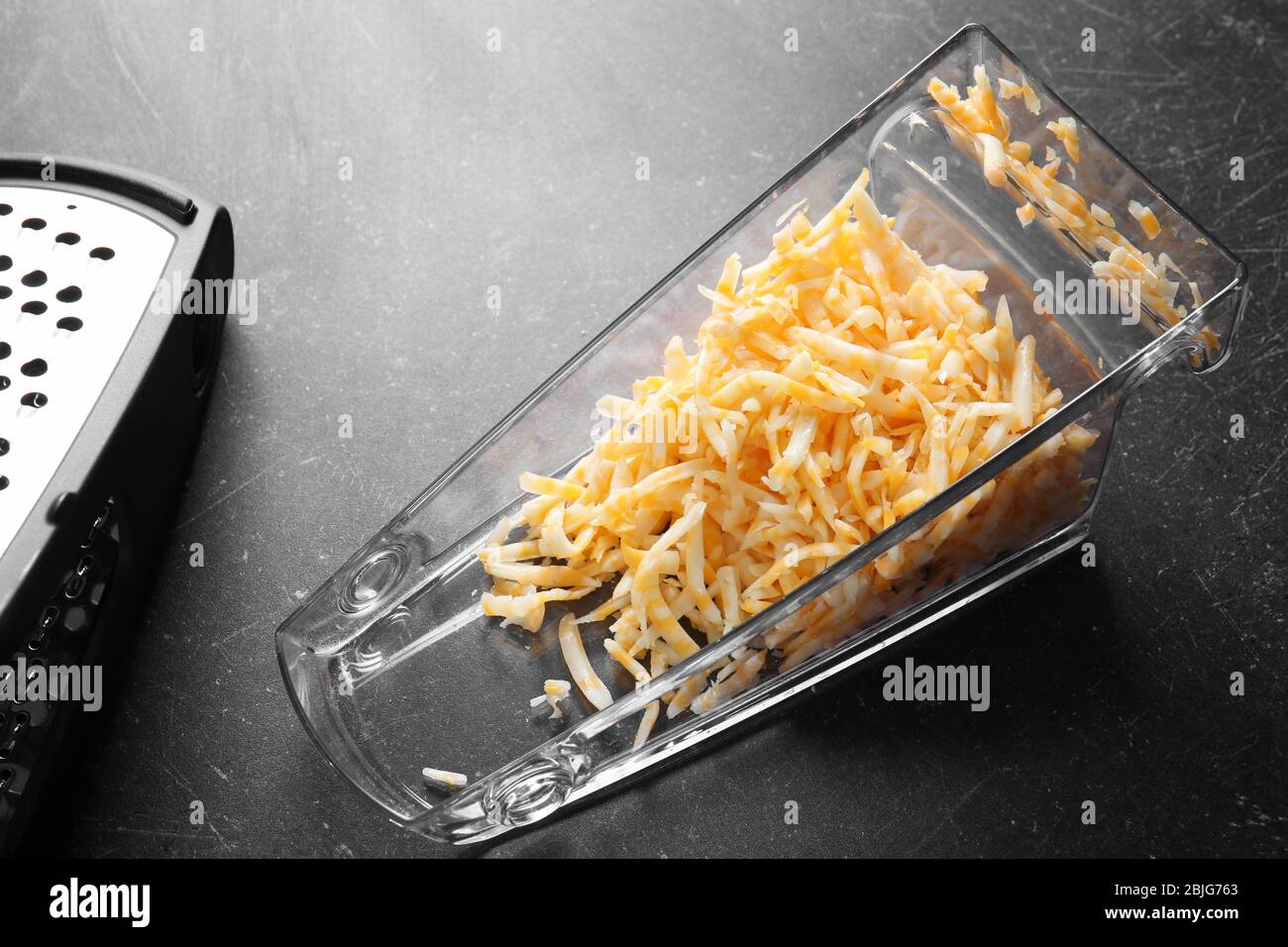 https://c8.alamy.com/comp/2BJG763/grated-cheese-in-plastic-container-on-table-2BJG763.jpg