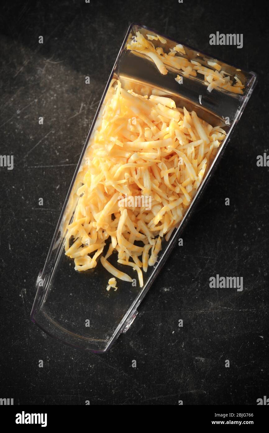 Plastic container with grated cheese on table Stock Photo - Alamy