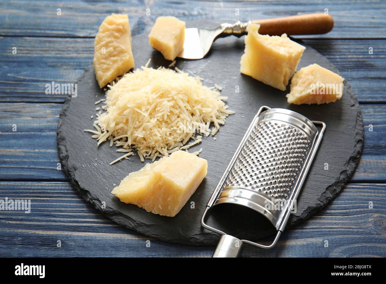 A block of Parmesan with a cheese grater on a slate plate Stock Photo -  Alamy