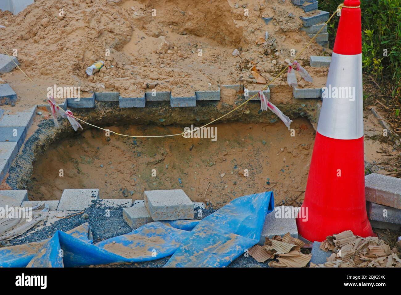 deep excavation in a foot footpath with sign pole Stock Photo - Alamy