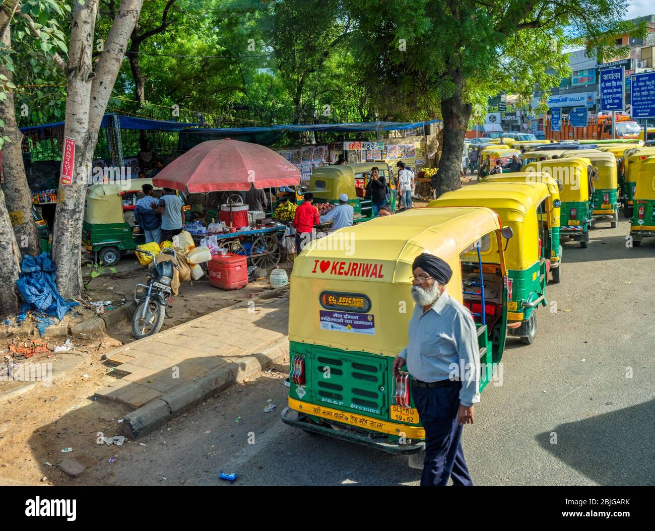 New Delhi / India - September 27, 2019: Sikh man in front of Tuk Tuks in the street in New Delhi, India. Tuk Tuks are painted with I Love Kejriwal slo Stock Photo