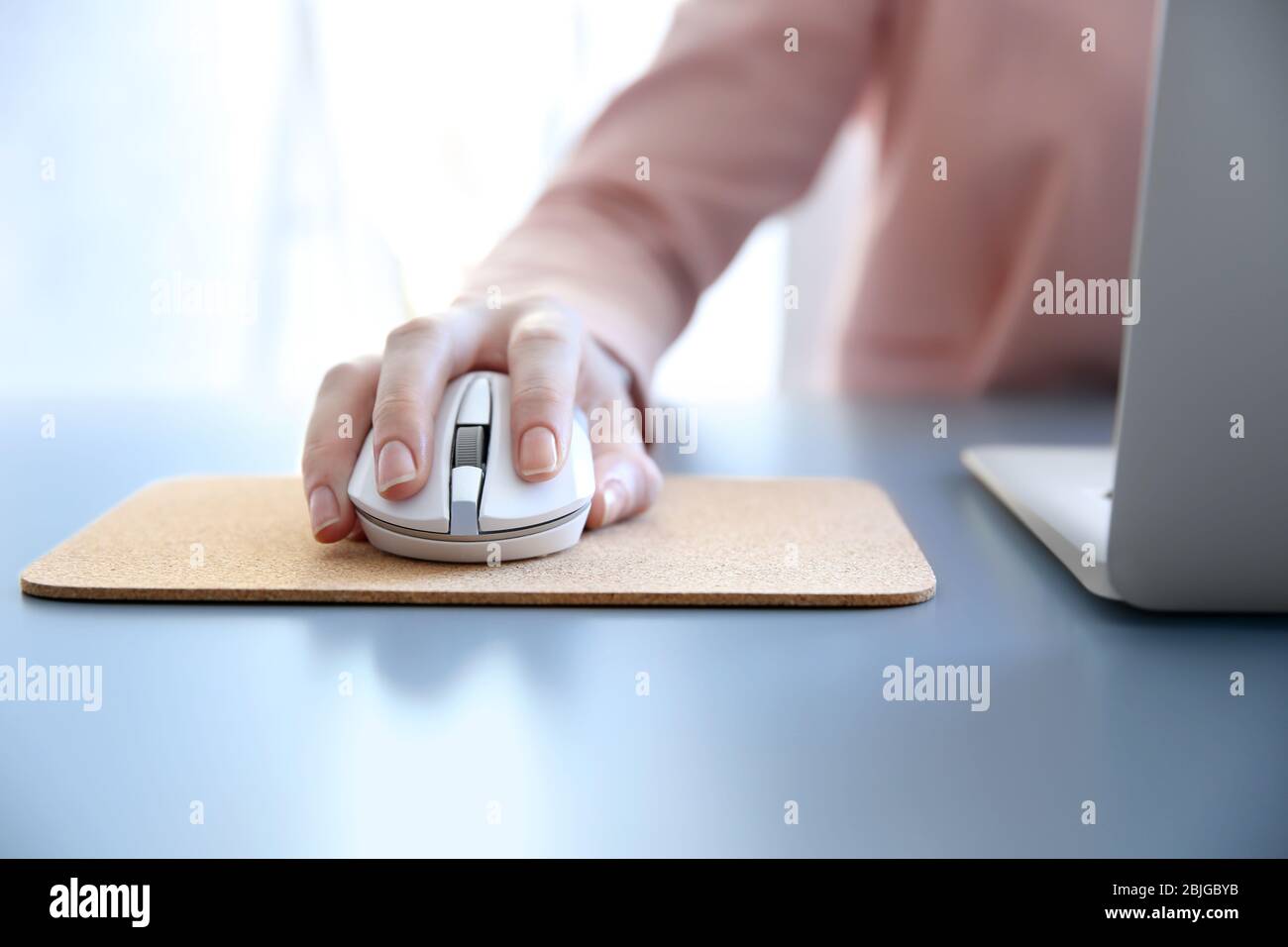 Woman using computer mouse with laptop on table Stock Photo