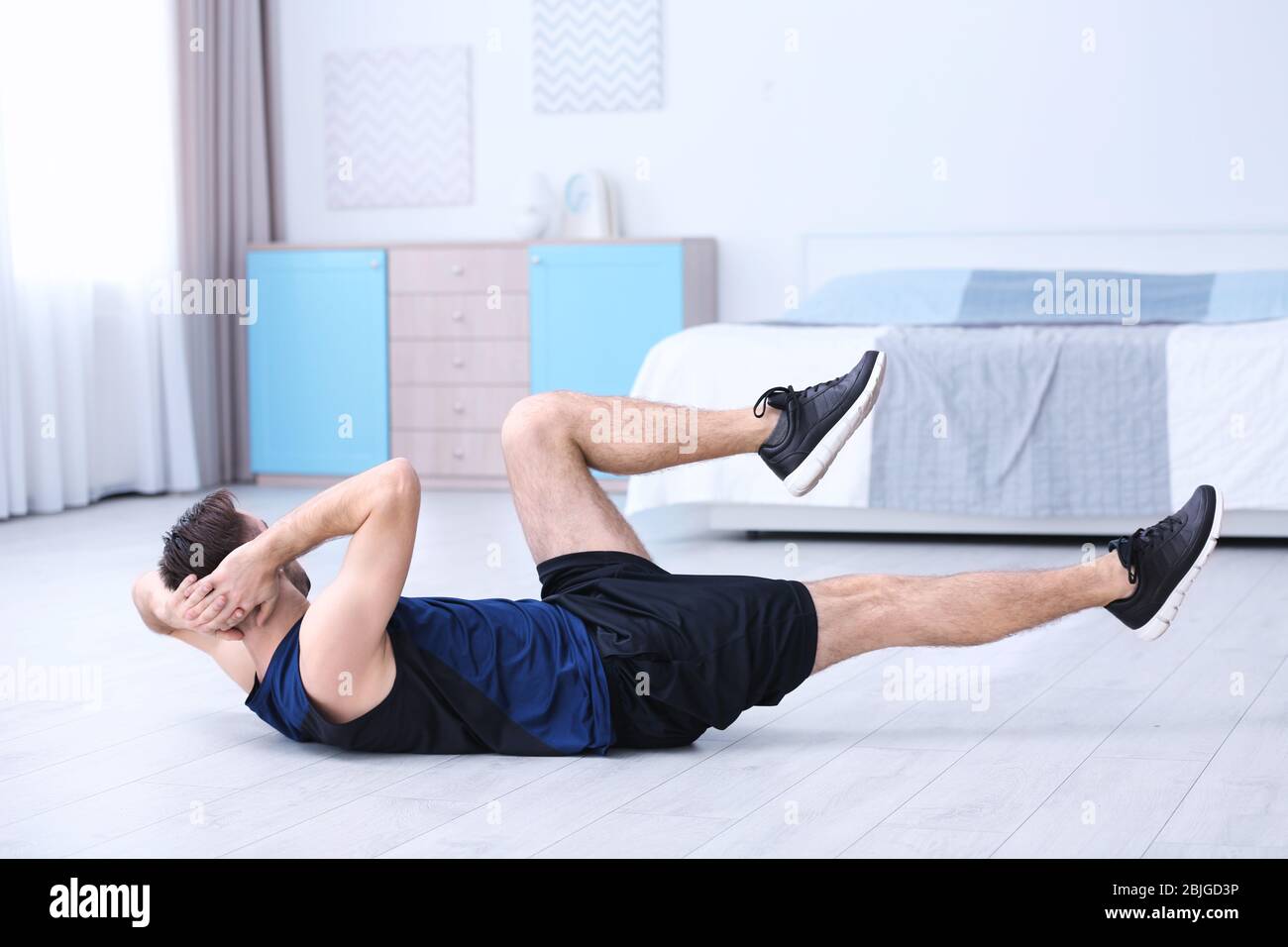 Young man doing bicycle crunch exercise at home Stock Photo