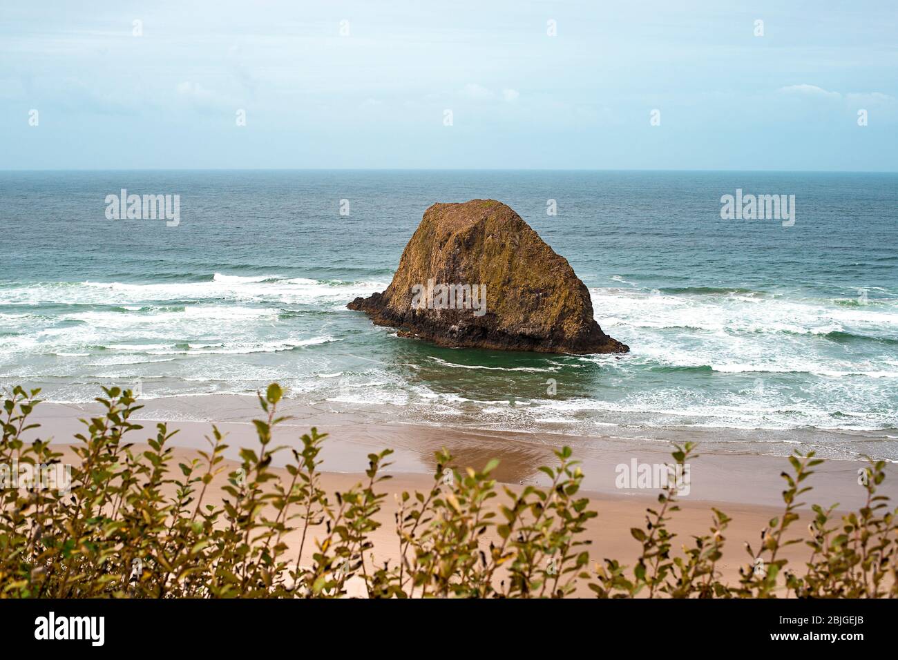 A peaceful Oregon beach coastline with Jockey Cap Rock in the middle, crashing ocean waves. Nature Landscape Background. Island near Tolovana Park, Ca Stock Photo