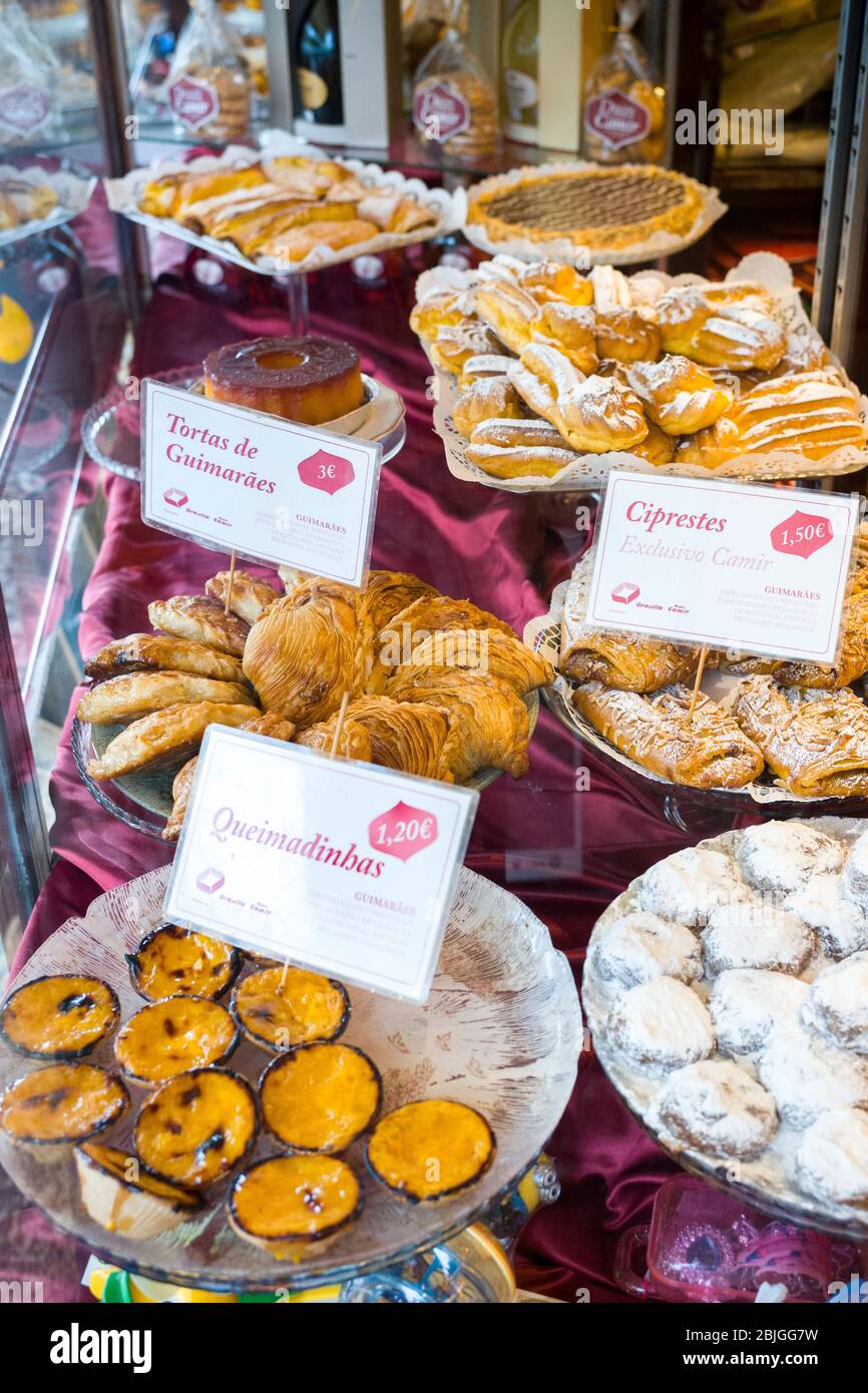 Traditional Portuguese pastries pastel de nata and tarts in window of Pastelaria Nova Camir pastry shop and cafe in Guimares, Por Stock Photo
