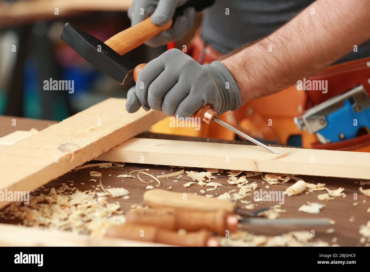 Carpenter with chisel and hammer in workshop, closeup Stock Photo