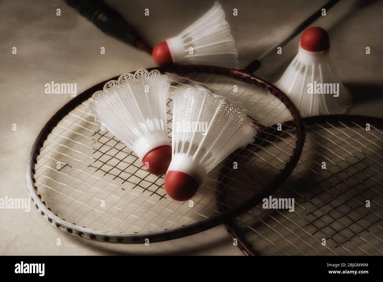 Badminton Still Life: Two rackets and shuttlecocks on gray surface with strong side light. Stock Photo