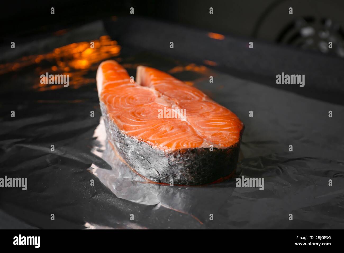 Baking sheet with foil and piece of salmon in oven Stock Photo - Alamy