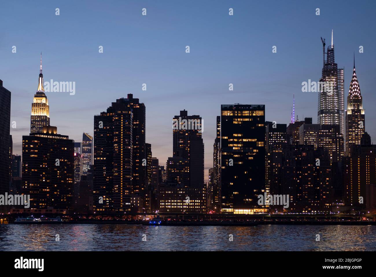 Evening view of the Manhattan Skyline with Empire State, One Vanderbilt, and Chrysler buildings form the East River in New York City Stock Photo