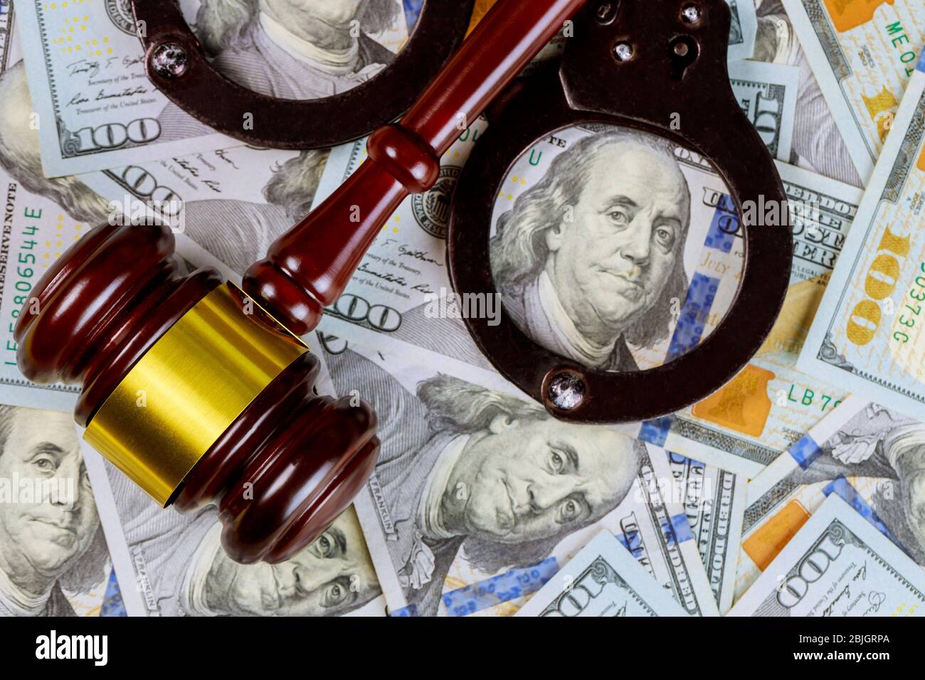 Legal justice desk on wooden judgment gavel with police handcuffs of many currency cash US dollars a law courtroom Stock Photo