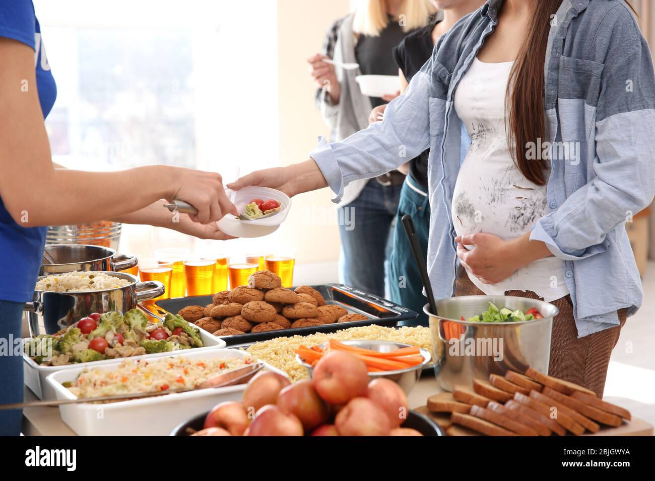 Pregnant woman receiving food from volunteer. Poverty concept Stock ...
