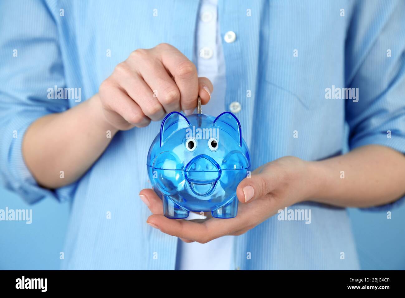 Young woman putting money into piggy bank, closeup Stock Photo - Alamy