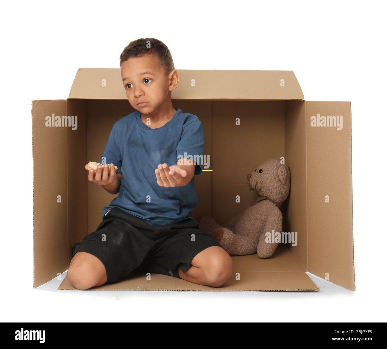 Cute little boy living in box on white background. Poverty concept Stock Photo