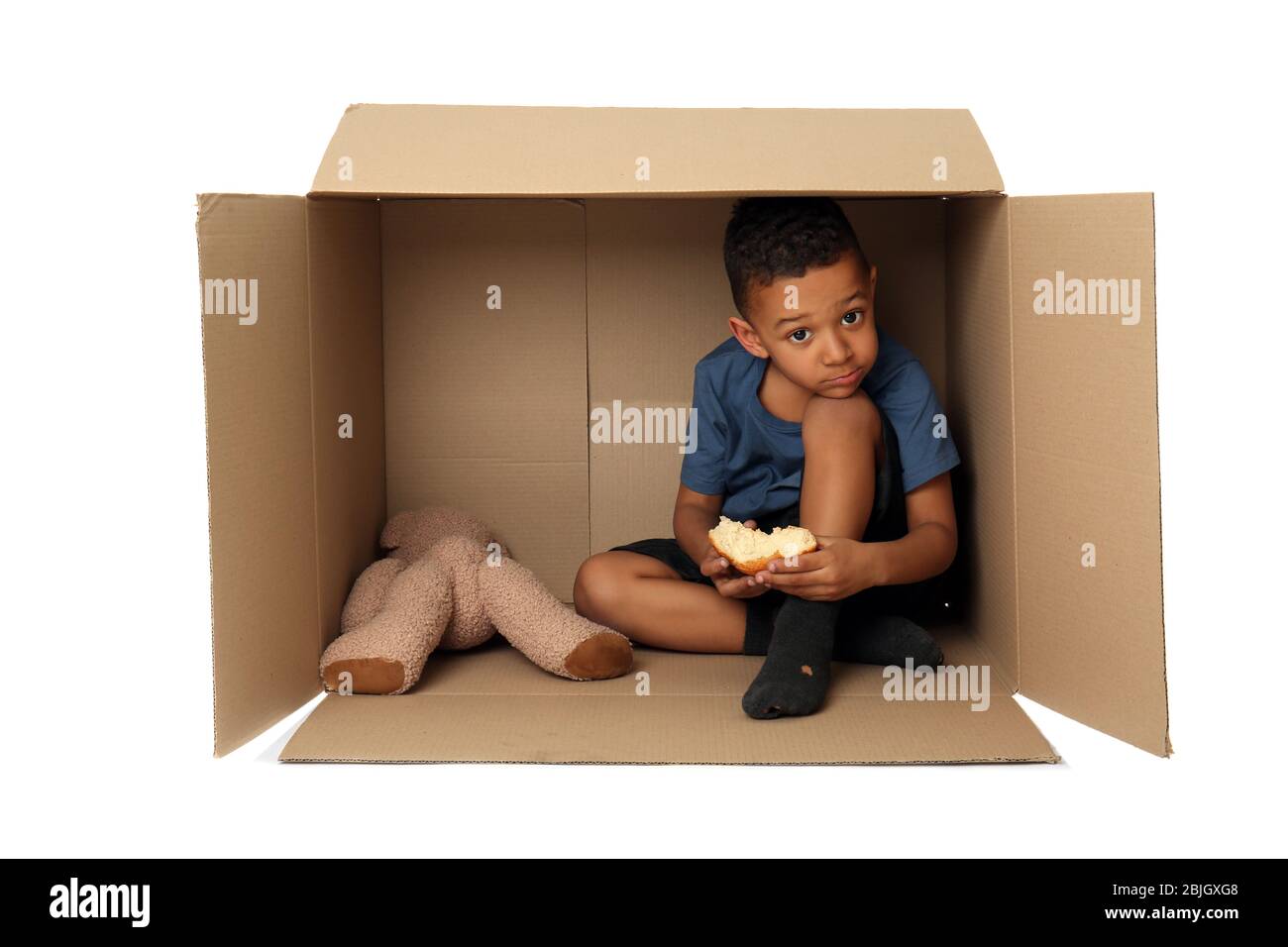 Cute little boy living in box on white background. Poverty concept Stock Photo