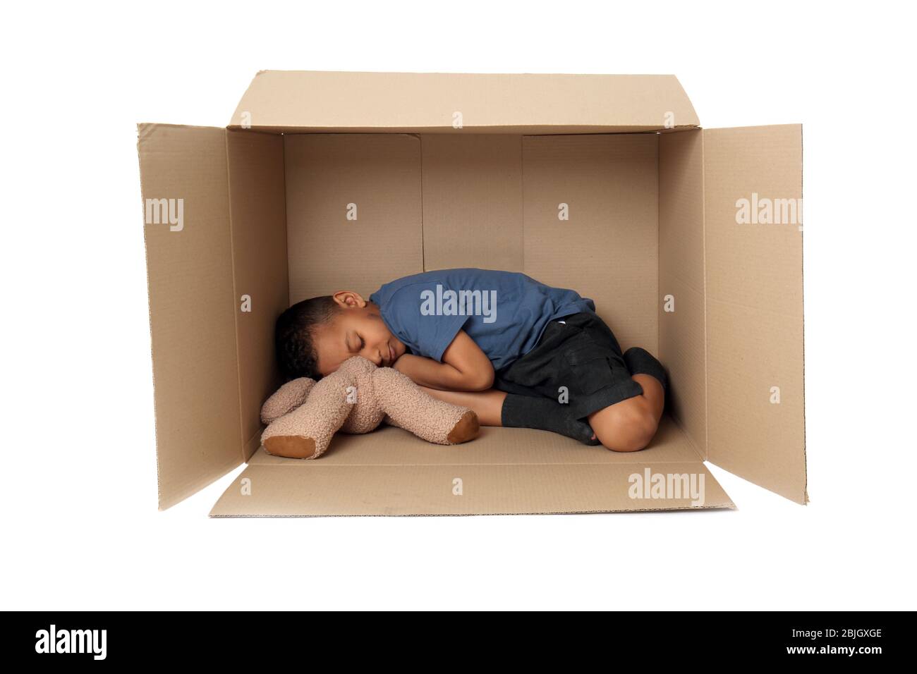 Cute little boy living in box on white background. Poverty concept Stock Photo