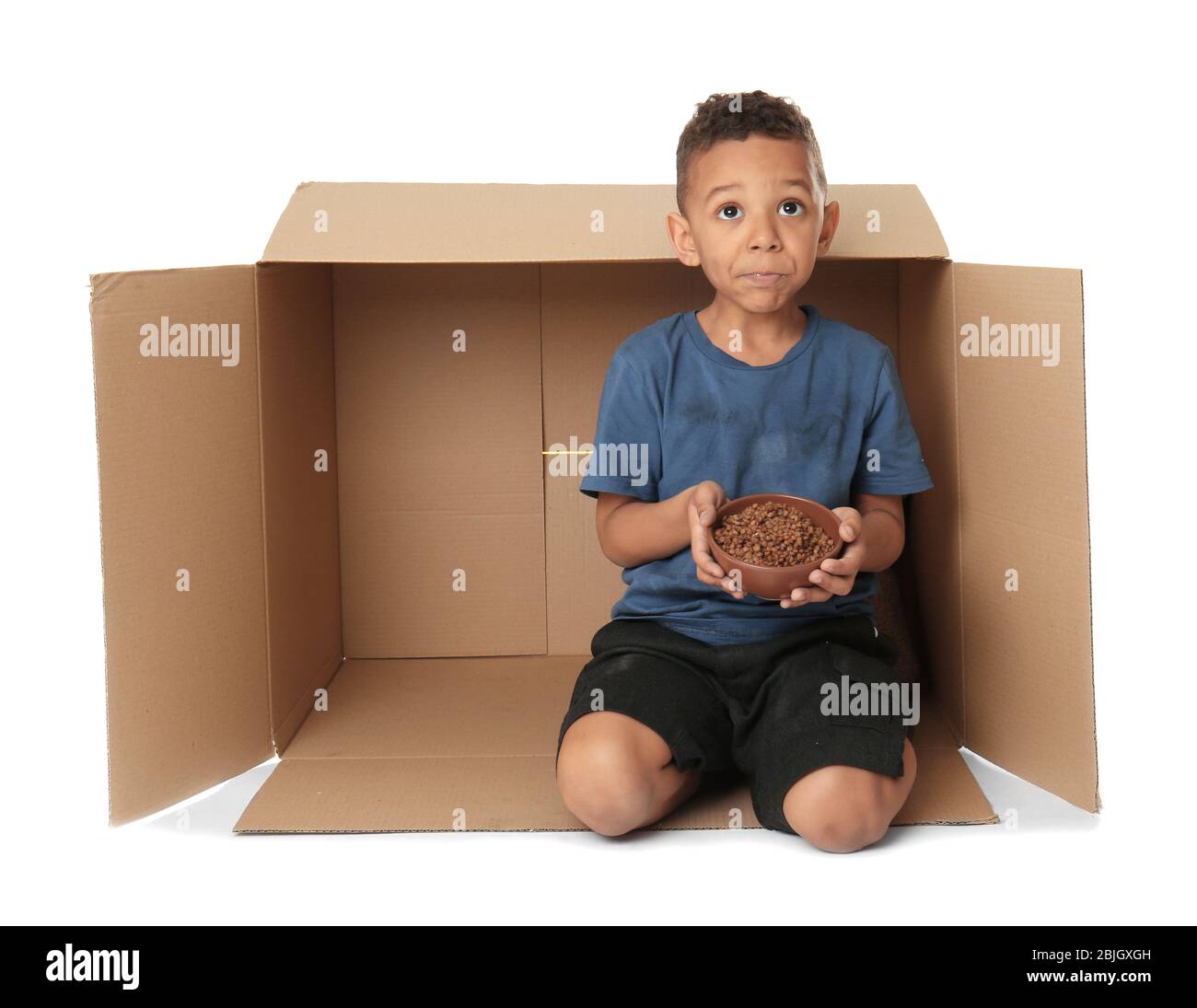 Cute little boy living in box on white background. Poverty concept Stock Photo