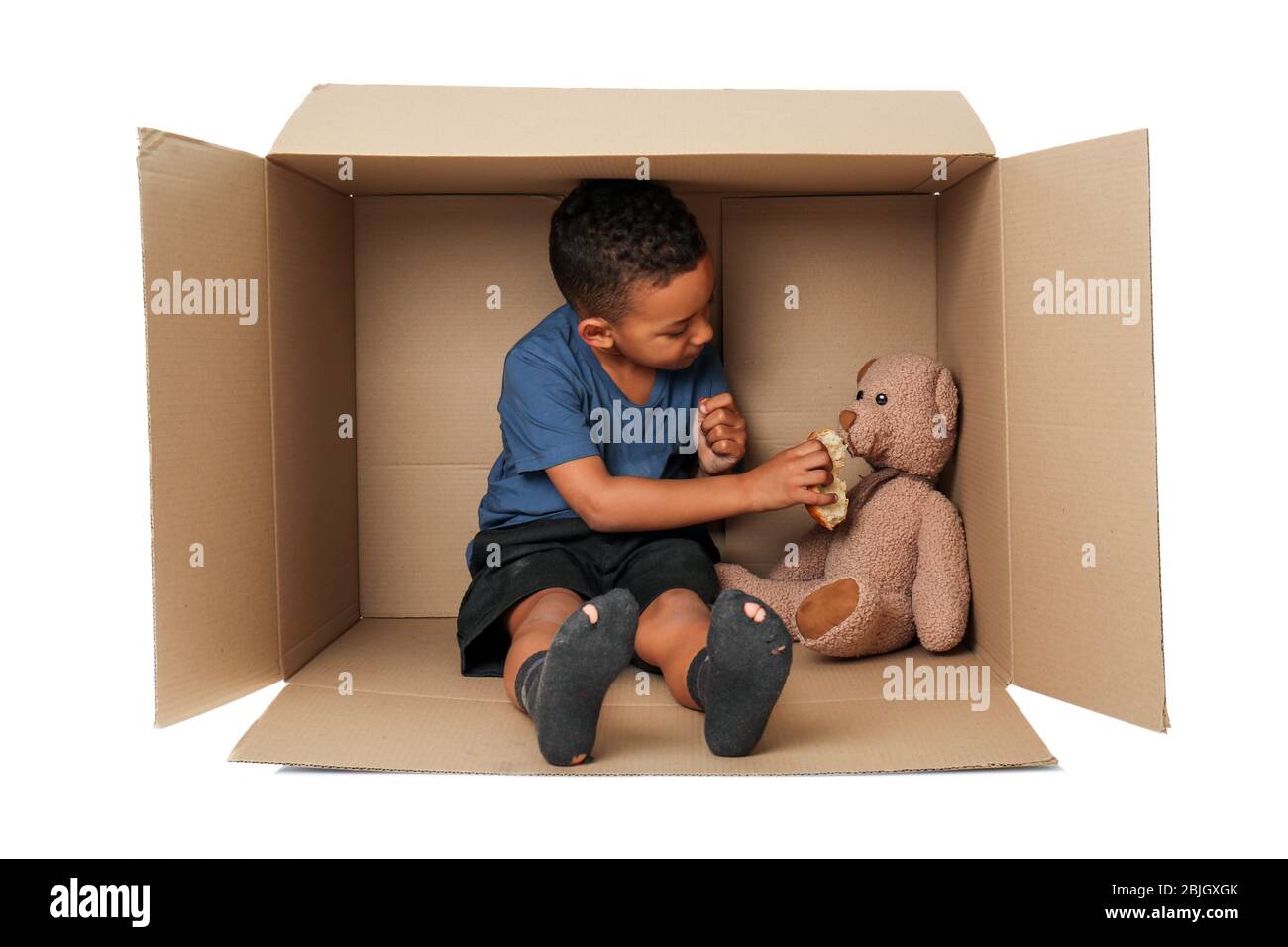 Cute little boy living in box on white background. Poverty concept Stock Photo