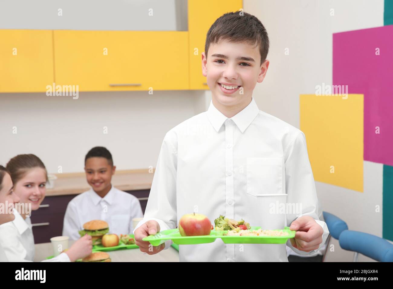 https://c8.alamy.com/comp/2BJGXR4/cute-boy-holding-tray-with-delicious-food-in-school-canteen-2BJGXR4.jpg