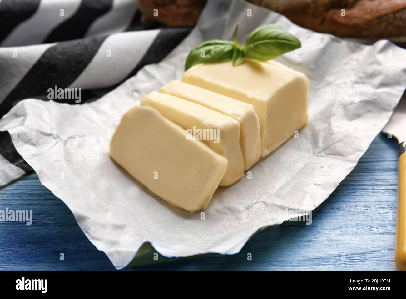 Piece of unwrapped butter on wooden table Stock Photo