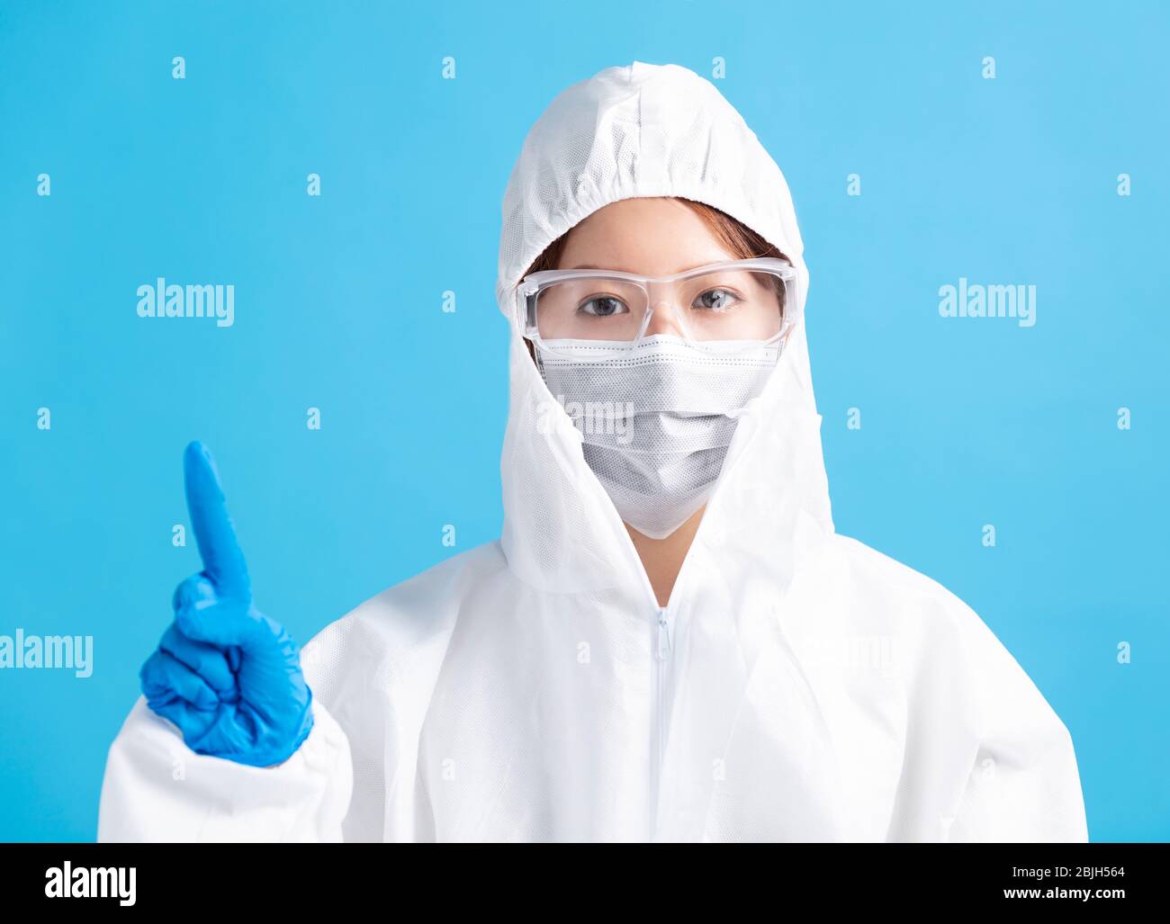 female nurse wearing medical mask with safety glasses and in white protective suit Stock Photo