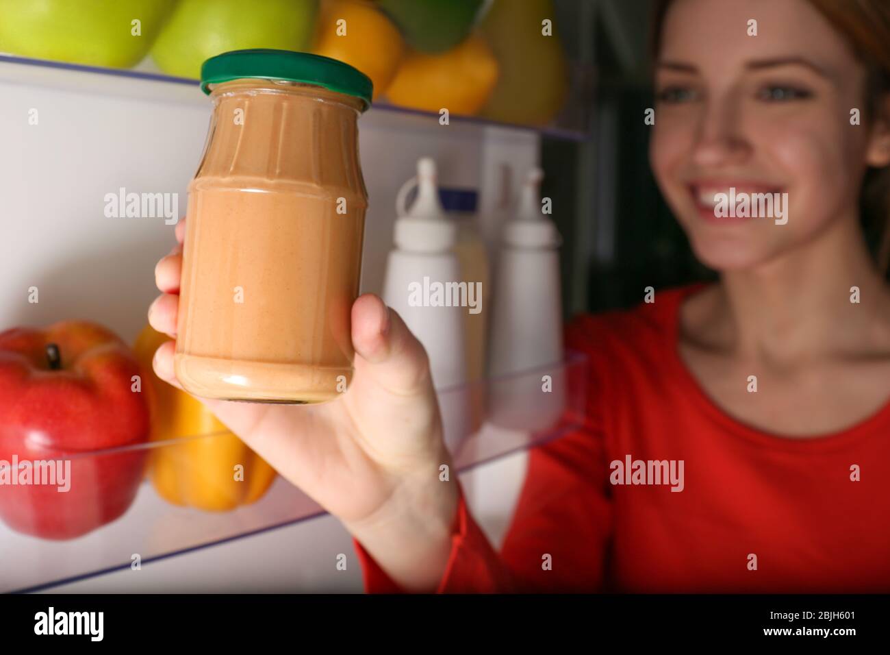 Young girl taking jar with sauce from fridge Stock Photo Alamy