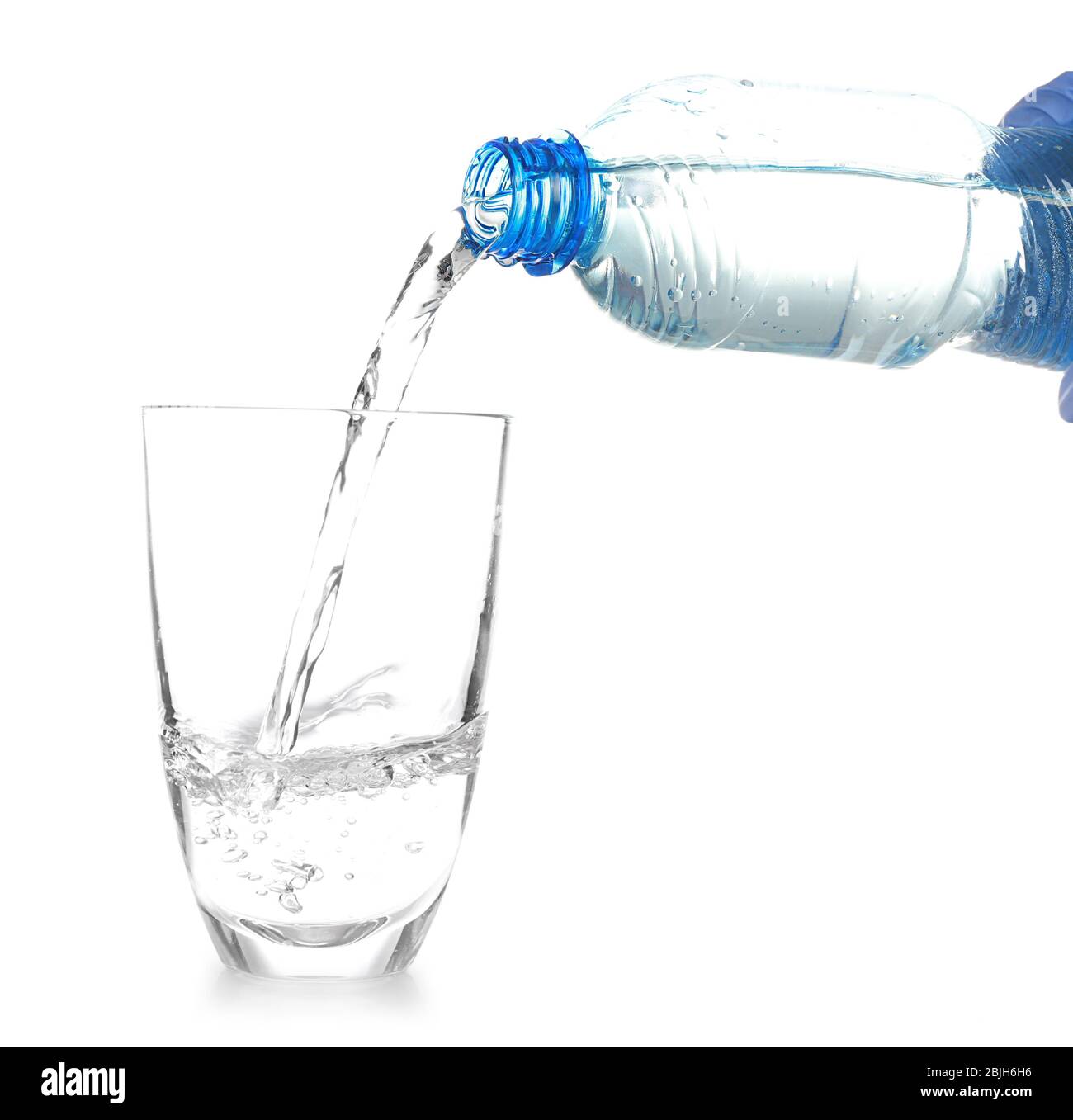 Water pouring from bottle into glass on white background Stock Photo
