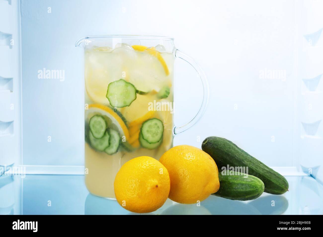 Jug of lemonade with cucumbers in fridge Stock Photo