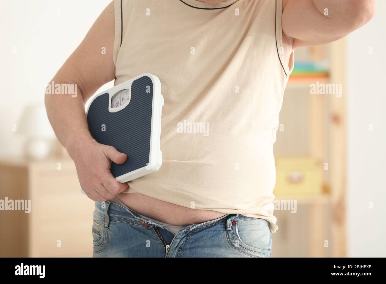 Fat man with scales at home, closeup. Weight loss concept Stock Photo